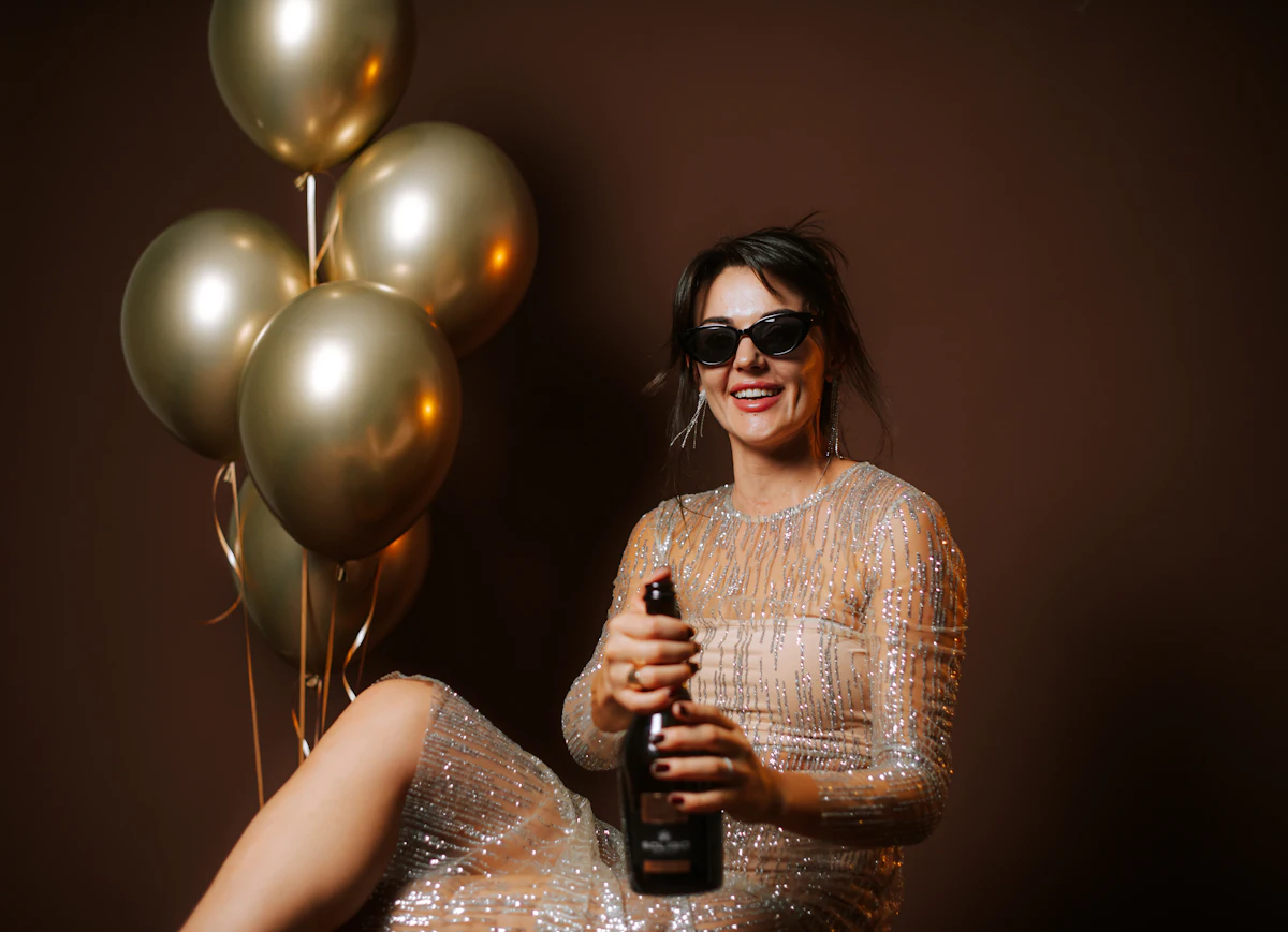Woman in sparkly dress opening champagne bottle with balloons — Champagne guns and champagne walls