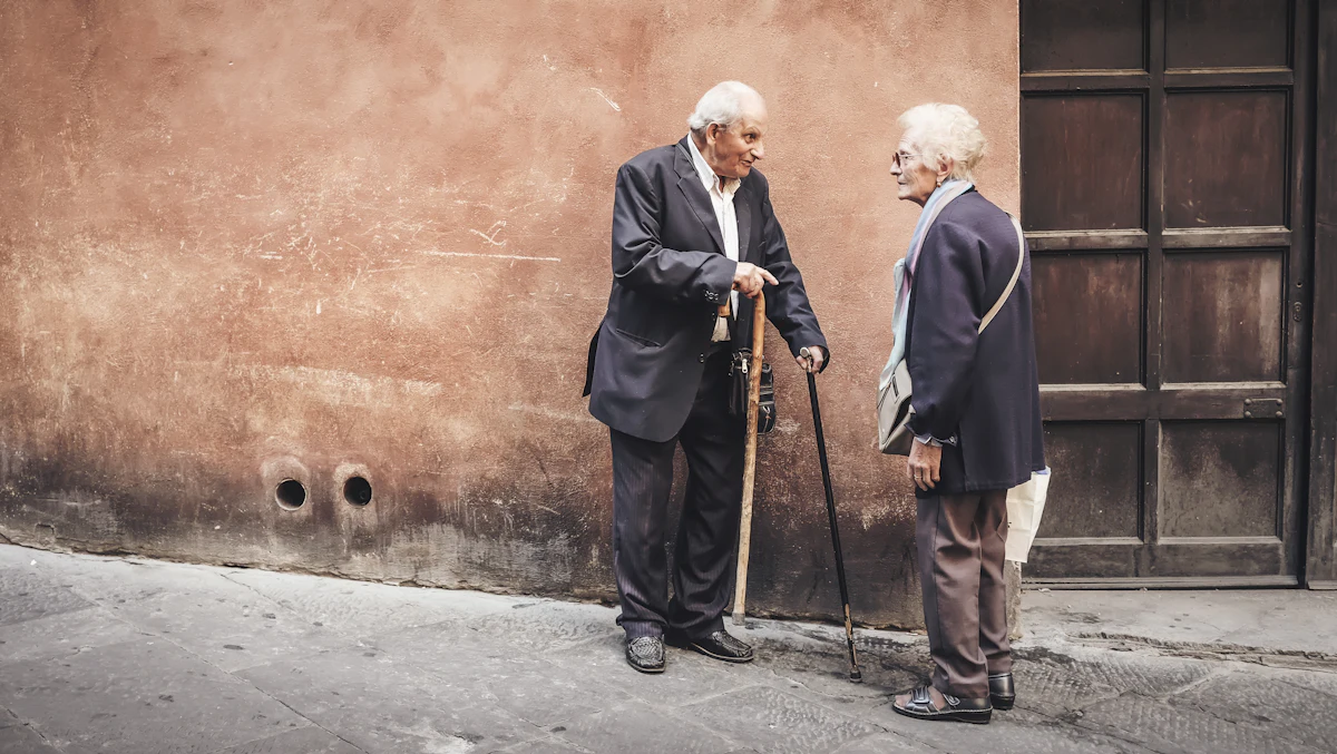 two person talking while standing near wall — A plan for the guests over seventy