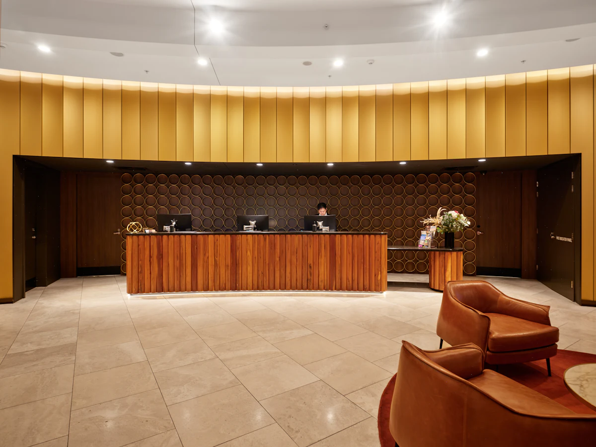 Hotel reception desk with modern wooden furniture and seating — A staffed guest desk in the hotel lobby