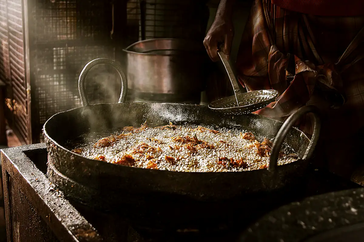 person cooking deep fried chicken close-up photo — The live jalebi and fafda counter