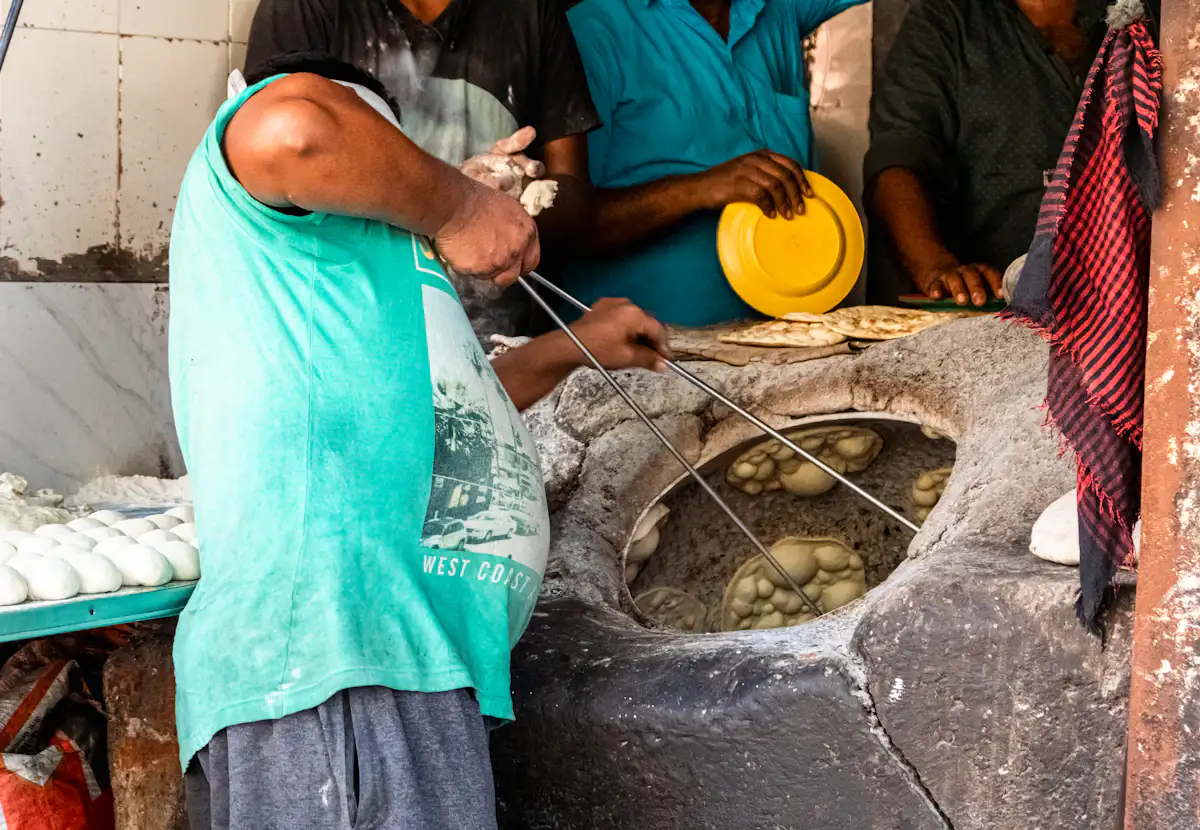 Man baking flatbread in a tandoor oven — Live tandoor and sigdi stations