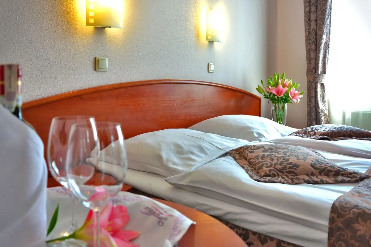 Elegant hotel room featuring a cozy bed, wine glasses, and floral decor, creating a welcoming atmosphere. — How many rooms you actually need