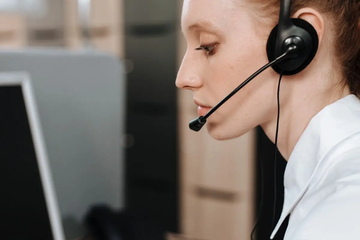 Close-up of a female call center agent using a headset while working at her desk. — How many people it takes to chase 300 guests