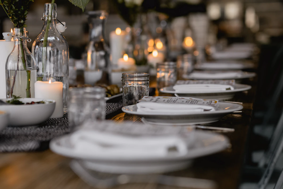 A long dining table set with white plates, candles, and glass bottles — A seating plan that survives the families